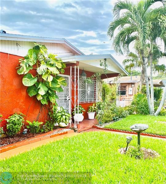 Front of House; lush green grass & tropical plants in big front yard at 3240 Thomas Ave, Miami, FL 33133