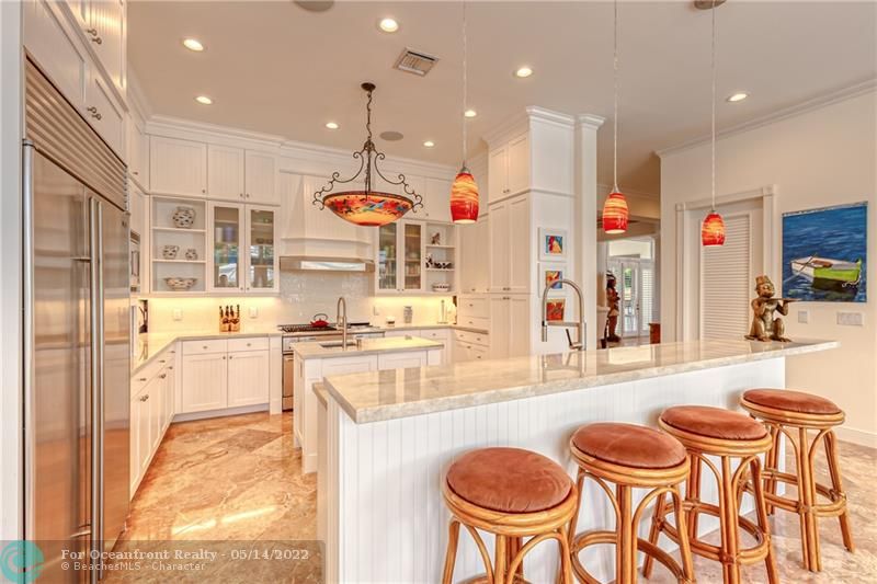 Open and bright custom kitchen with marble counters and large breakfast bar