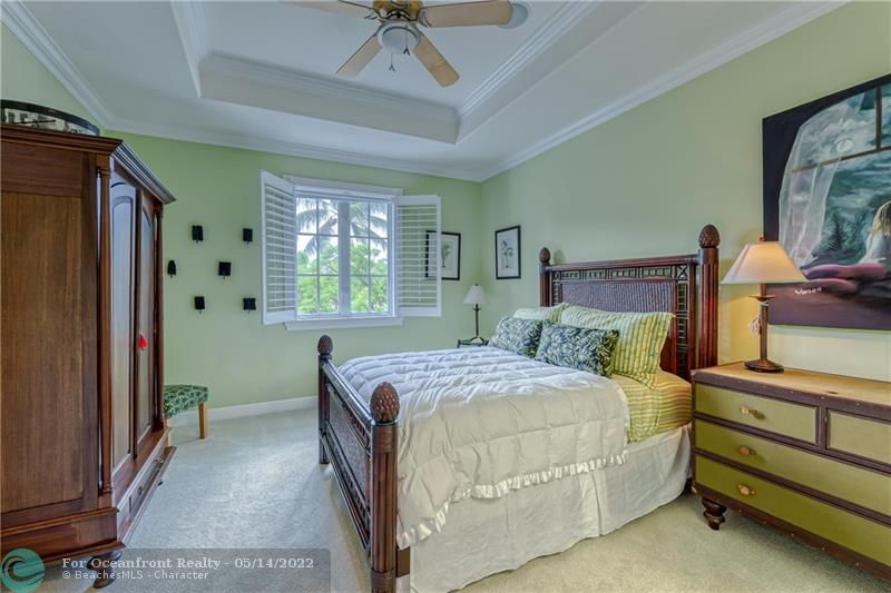 Large upstairs bedroom with recessed ceiling with fan and plantation shutters