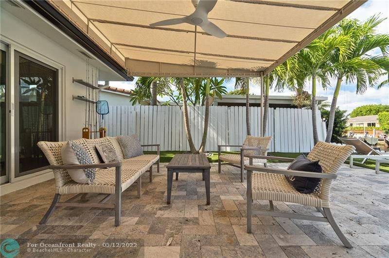 Tumbled marble paver patio with canvas awnings, fan, tv and drink station.